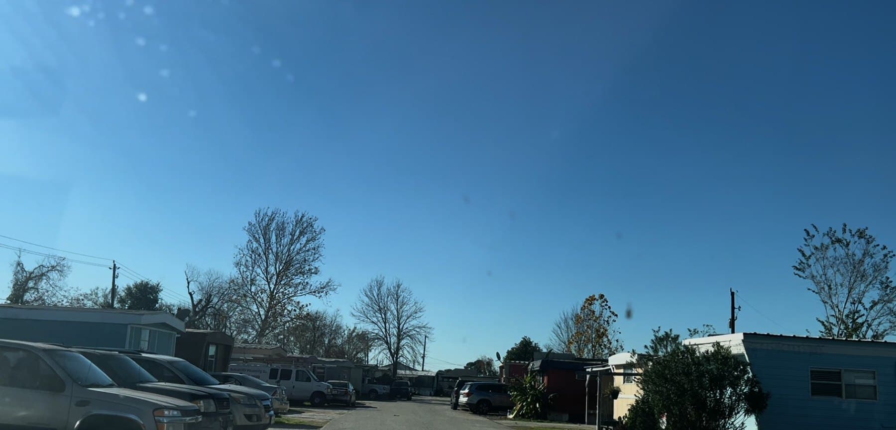 Street view inside Woodforest Mobile Home Park with homes and parked vehicles