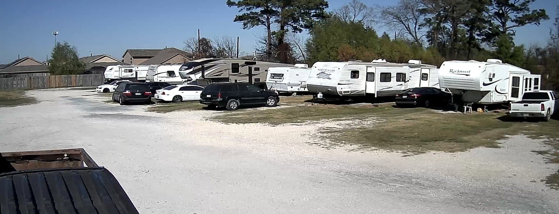 Wide view of RV spaces with gravel drive and parked RVs at Woodforest RV Park